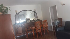 A dining area with a wooden table, chairs, a mirror, and a fan. - Apartment Paris ( Le Kremlin-Bicêtre ) (Le Kremlin-Bicêtre)