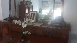 A wooden dresser with a mirror, a framed picture, and a vase with white flowers. - Apartment Paris ( Le Kremlin-Bicêtre ) (Le Kremlin-Bicêtre)