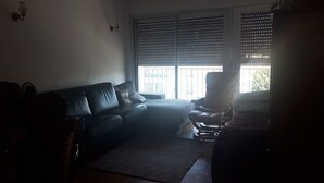 A living room with a sofa, a chair, and a large window with blinds. - Apartment Paris ( Le Kremlin-Bicêtre ) (Le Kremlin-Bicêtre)