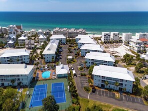 Um resort com vários edifícios, quadra de tênis e piscina.