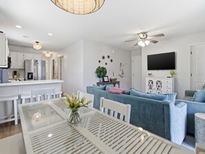 A modern kitchen with white cabinets, a built-in refrigerator, and a dining area with a glass table and chairs. - Beachside Villas #821 | Pet Friendly Luxe Villa, Gulf View + Amenities (Seagrove Beach)