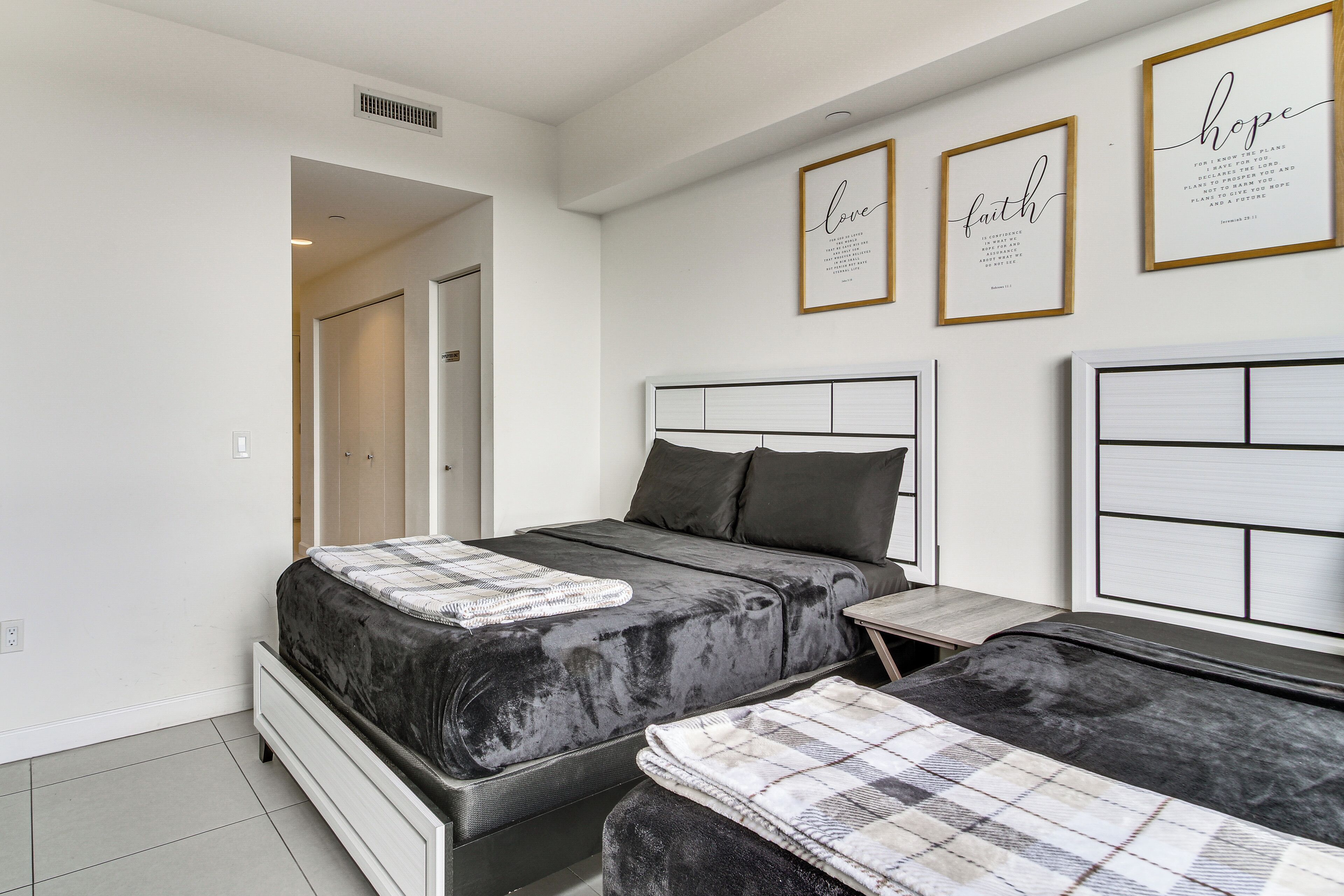Camera da letto moderna con due letti, un comodino e una parete con citazioni motivazionali incorniciate.