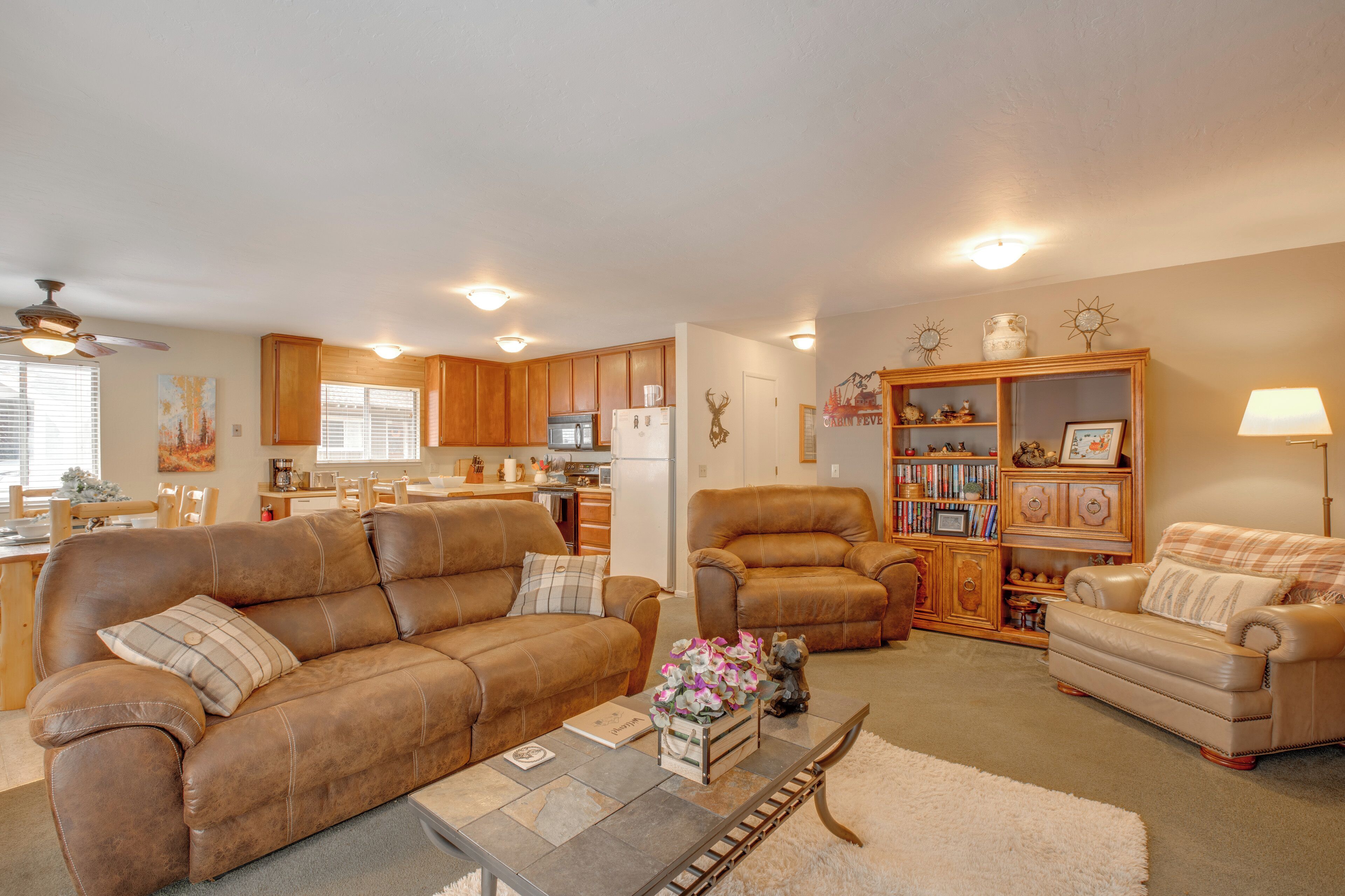 A living room with a brown leather sofa, a coffee table, and a bookshelf.