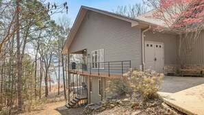 Une maison à deux étages avec un balcon, un garage et un mur de soutènement en pierre.