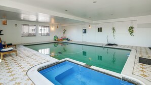 An indoor swimming pool with a tiled floor, a smaller pool area, and a door leading to another room. - Bay Area Family Home w/ Indoor Pool + Game Room (South San Francisco)
