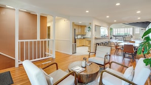 A spacious living area with a high ceiling, wooden flooring, and a mix of modern and classic furniture.