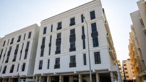 Ein mehrstöckiges Gebäude mit einer symmetrischen Fassade, großen Fenstern und einem zentralen Eingang.
