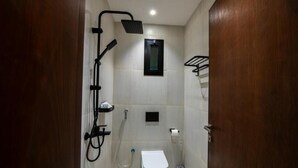 Ein kleines Badezimmer mit Dusche, Toilette und einem Ablagefach für Pflegeartikel.