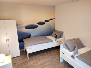 Une chambre à coucher comprenant un lit, des tables de chevet, une armoire et une fresque murale.