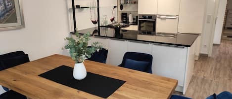 A modern kitchen with white cabinets, a black countertop, and a built-in oven.