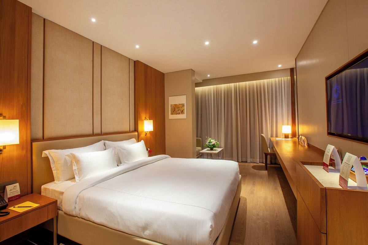 Een hotelkamer met een groot bed, nachtkastjes, een bureau en een televisie.