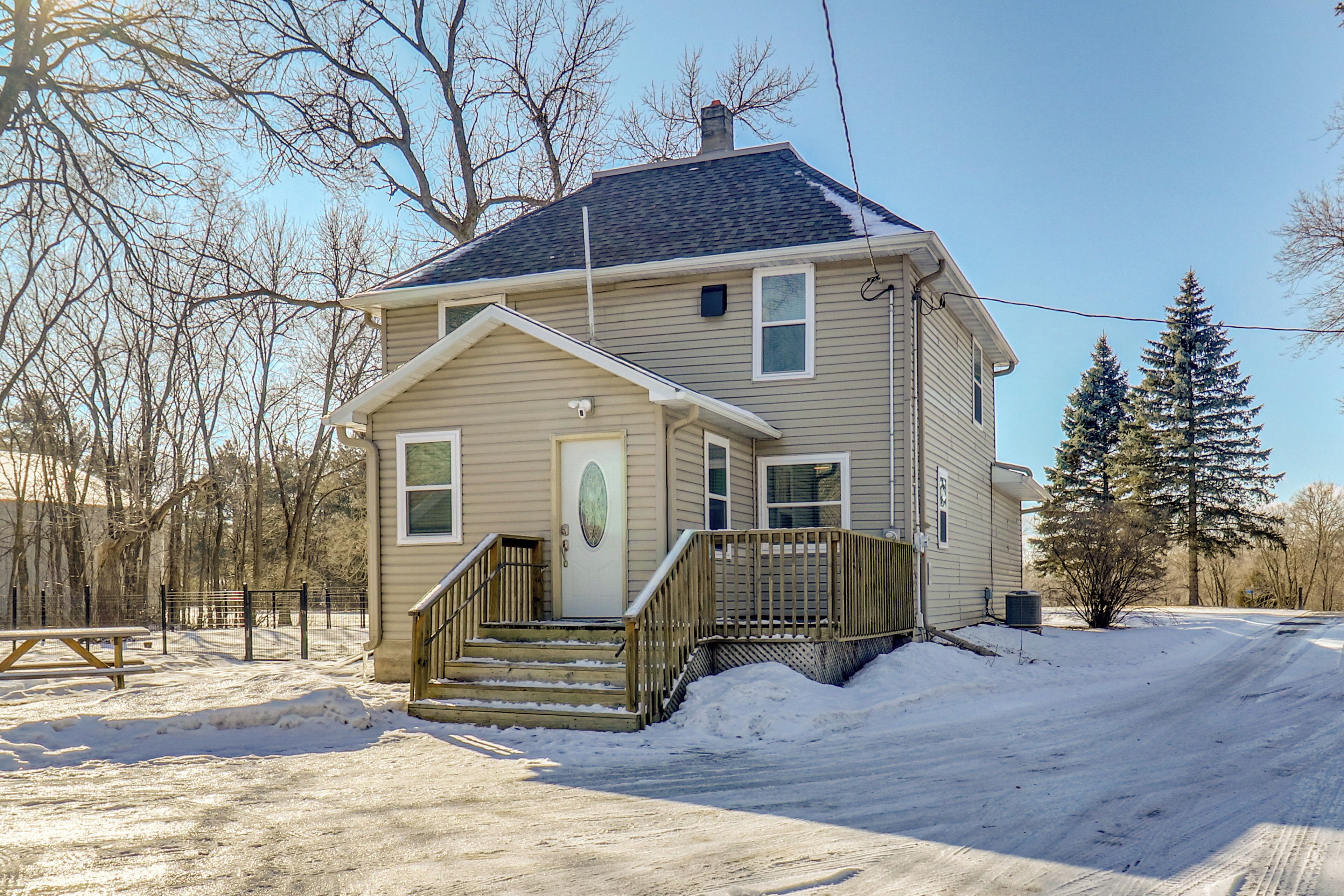 A two-story house with a front porch, a staircase, and a snow-covered driveway.
