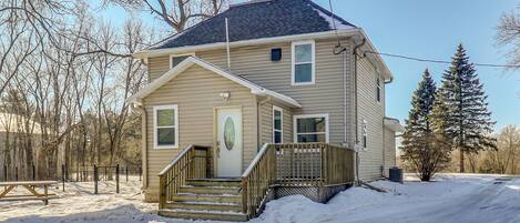 A two-story house with a front porch, a staircase, and a snow-covered driveway.