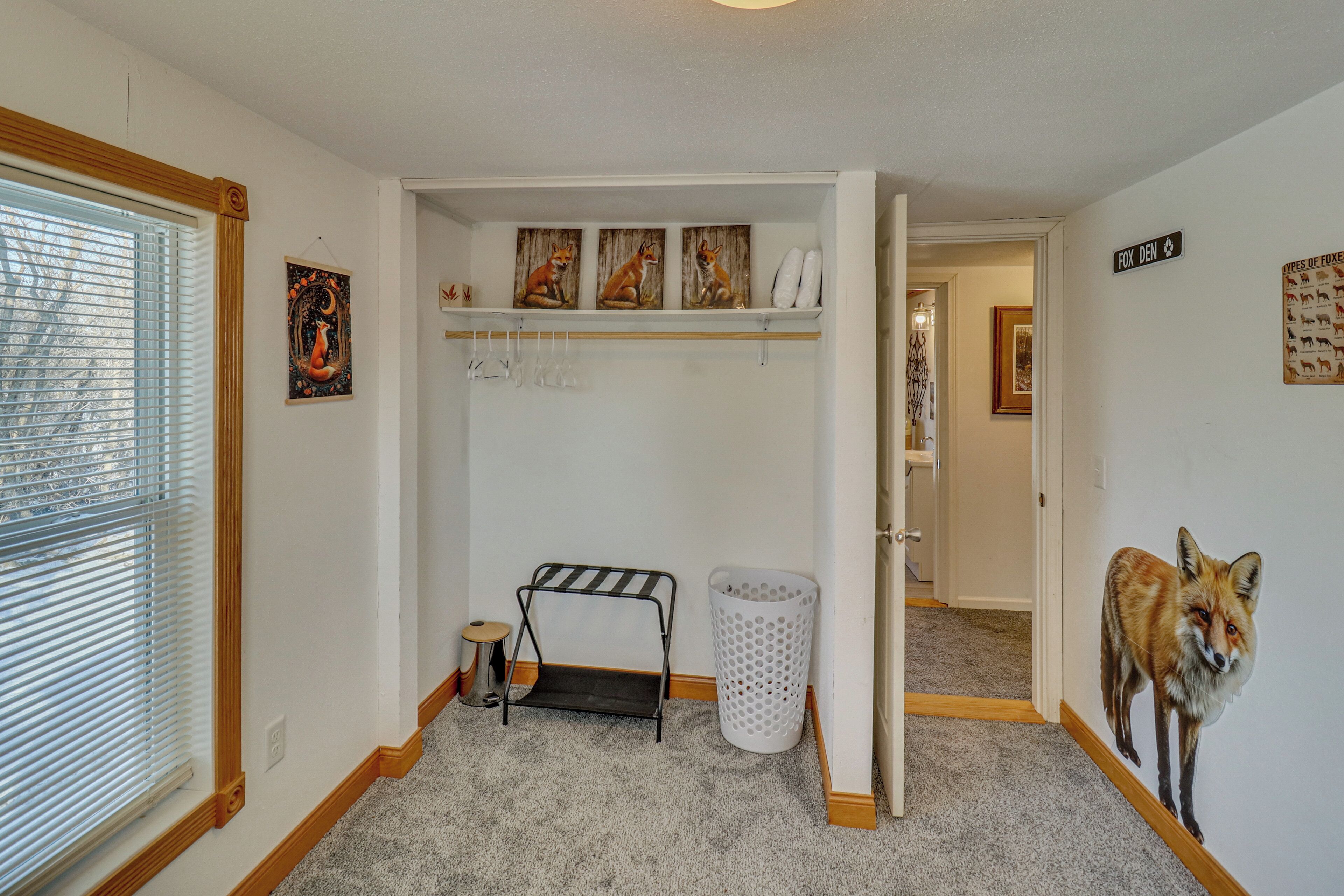 A hallway with a laundry basket, a hanging rack, and a fox mural on the wall.