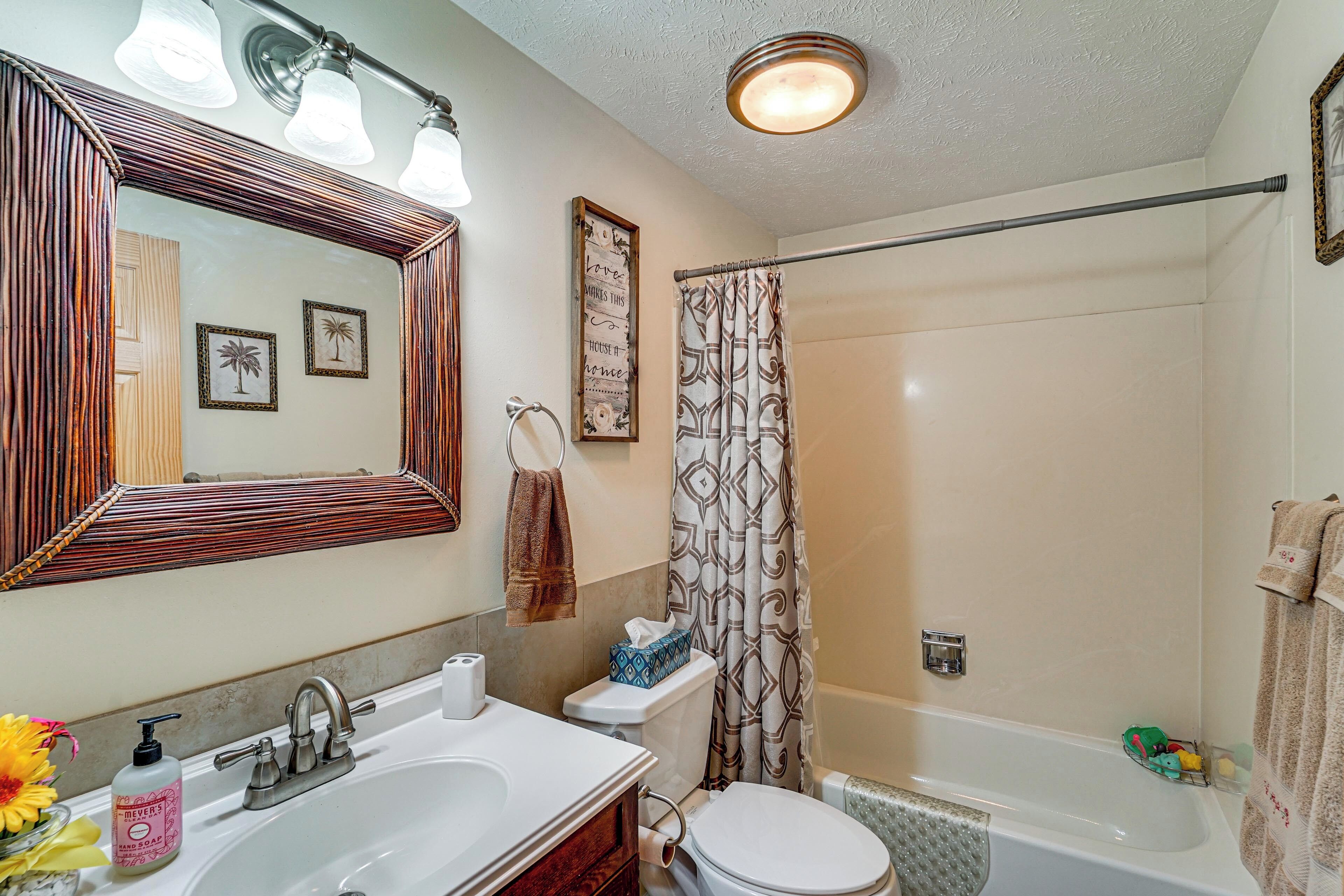 A bathroom with a sink, mirror, toilet, shower, and towel rack.