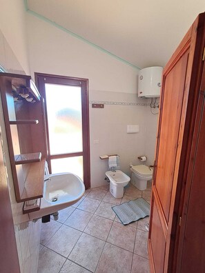 Ein Badezimmer mit Waschbecken, Bidet, Toilette und einem Fenster.