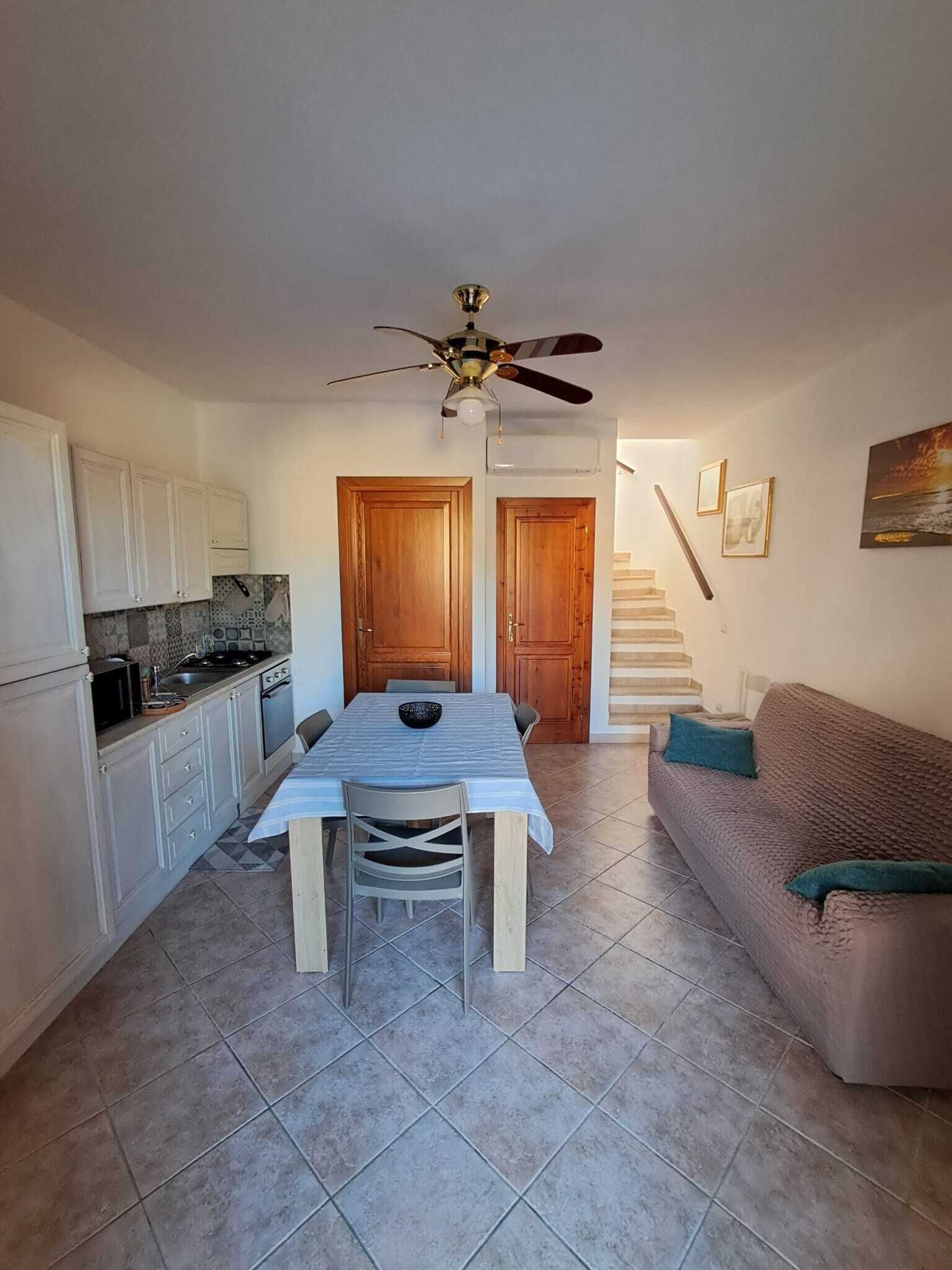 Een ruimtelijk ingerichte leefruimte met een eethoek, kitchenette en een trap naar een hoger niveau.