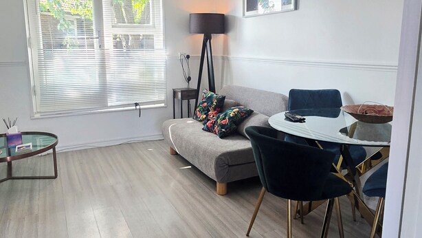 Ein modernes Wohnzimmer mit einer Couch, einem Esstisch und einer Stehlampe.