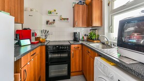 Eine Küche mit Holzausstattung, einer roten Kaffeemaschine, einem schwarzen Backofen, einem Geschirrspüler und einem Fenster mit Aussicht.