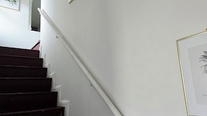 Eine Treppe mit dunklen Stufen und weißen Wänden, die zu einer oberen Etage führt.