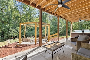A covered patio area with a wooden pergola, outdoor seating, and a hot tub. - < 1 Mi to Lake Blue Ridge: Forest-view Gem w/ Deck (Morganton)
