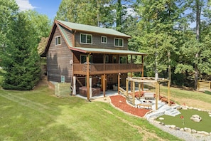 A two-story wooden cabin with a balcony, a deck, and a fire pit area. - < 1 Mi to Lake Blue Ridge: Forest-view Gem w/ Deck (Morganton)