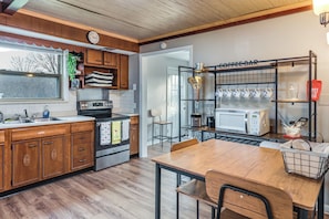 A kitchen with wooden cabinets, a stainless steel stove, a coffee bar with mugs, and a dining table. - Warren County Launchpad: Pet-friendly Lebanon Apt (South Lebanon)