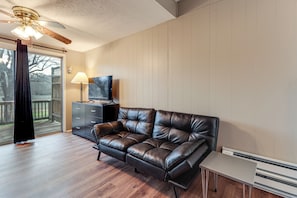 A living room with a leather sofa, a TV on a stand, a lamp, and a heater. - Warren County Launchpad: Pet-friendly Lebanon Apt (South Lebanon)