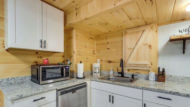 A compact kitchen with white cabinets, a built-in microwave, a coffee maker, and a dishwasher. - Escape to Nature! Cozy Blue Ridge Mtn Retreat (Epworth)