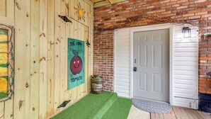A wooden wall with a tomato-themed poster, a white door, and a brick wall. - Escape to Nature! Cozy Blue Ridge Mtn Retreat (Epworth)