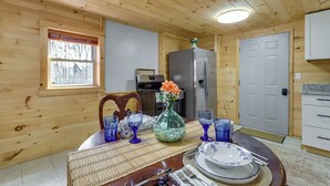 A wooden interior with a dining table set for four, a refrigerator, and a window with blinds. - Escape to Nature! Cozy Blue Ridge Mtn Retreat (Epworth)