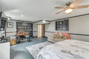 Un dormitorio con cama, escritorio, silla, ventilador de techo y estantes empotrados.