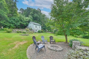 A rustic outdoor seating area with Adirondack chairs, a stone fire pit, and a stone wall. - Hike, Bike & Relax: Huckleberry Hill Home w/ Yard! (Avon)