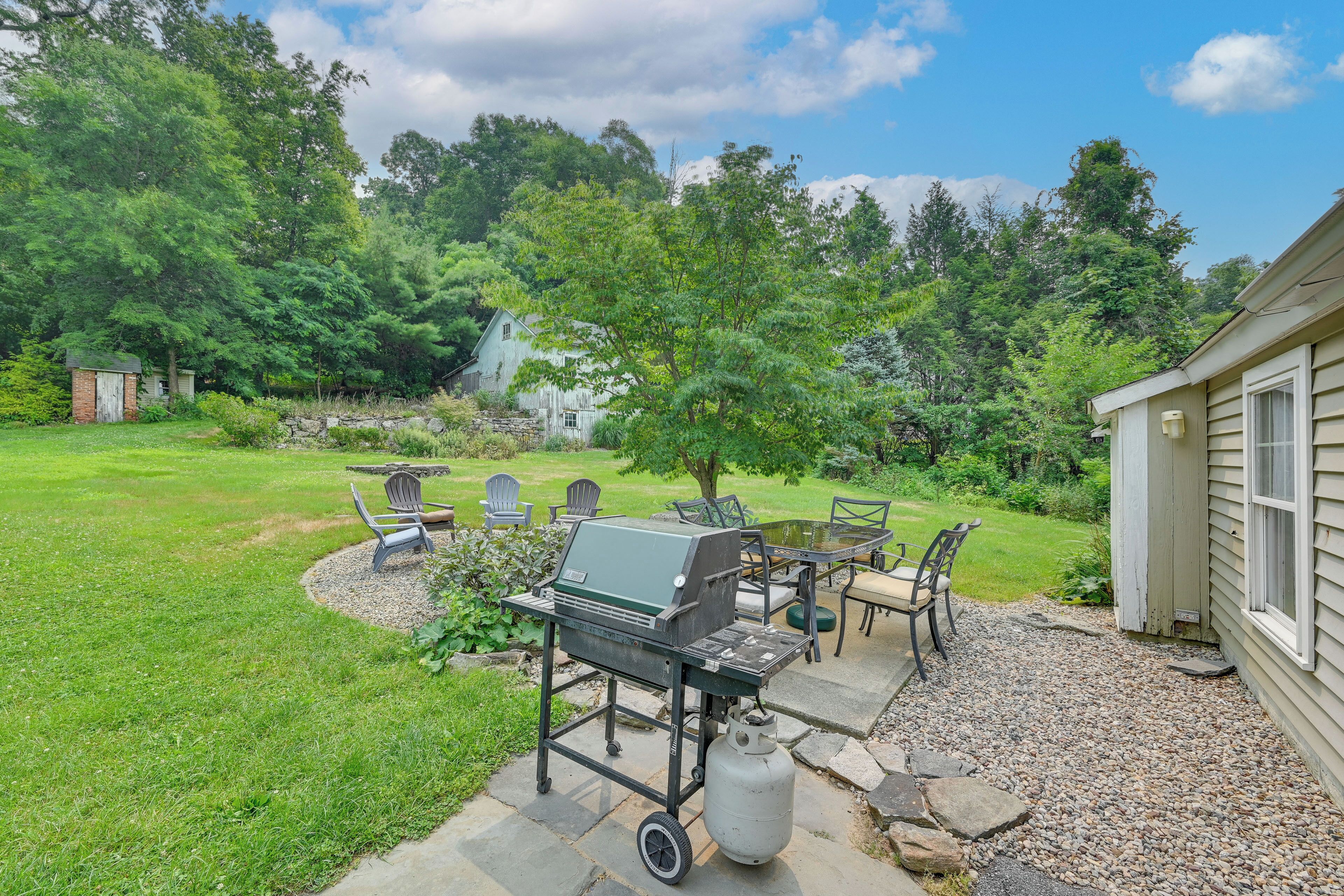 A backyard with a barbecue grill, outdoor seating, and a stone pathway.