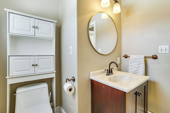 A bathroom with a toilet, a sink with a mirror, and a cabinet. - Hike, Bike & Relax: Huckleberry Hill Home w/ Yard! (Avon)