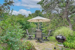 An outdoor patio with a table and chairs, an umbrella, and a grill. - Hike, Bike & Relax: Huckleberry Hill Home w/ Yard! (Avon)