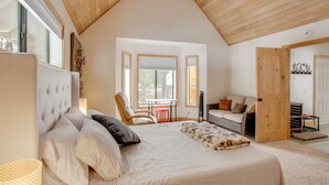 A bedroom with a large bed, a chair, a table, and a door leading to another room. - 5 Mi to Soda Springs Mtn Resort: Forest-view Gem! (Truckee)