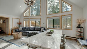 A spacious kitchen with a large island, high windows, and a modern chandelier. - 5 Mi to Soda Springs Mtn Resort: Forest-view Gem! (Truckee)