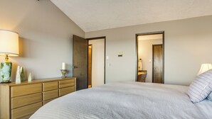 Un dormitorio con una cama grande, un aparador de madera y dos puertas que dan a otras habitaciones.
