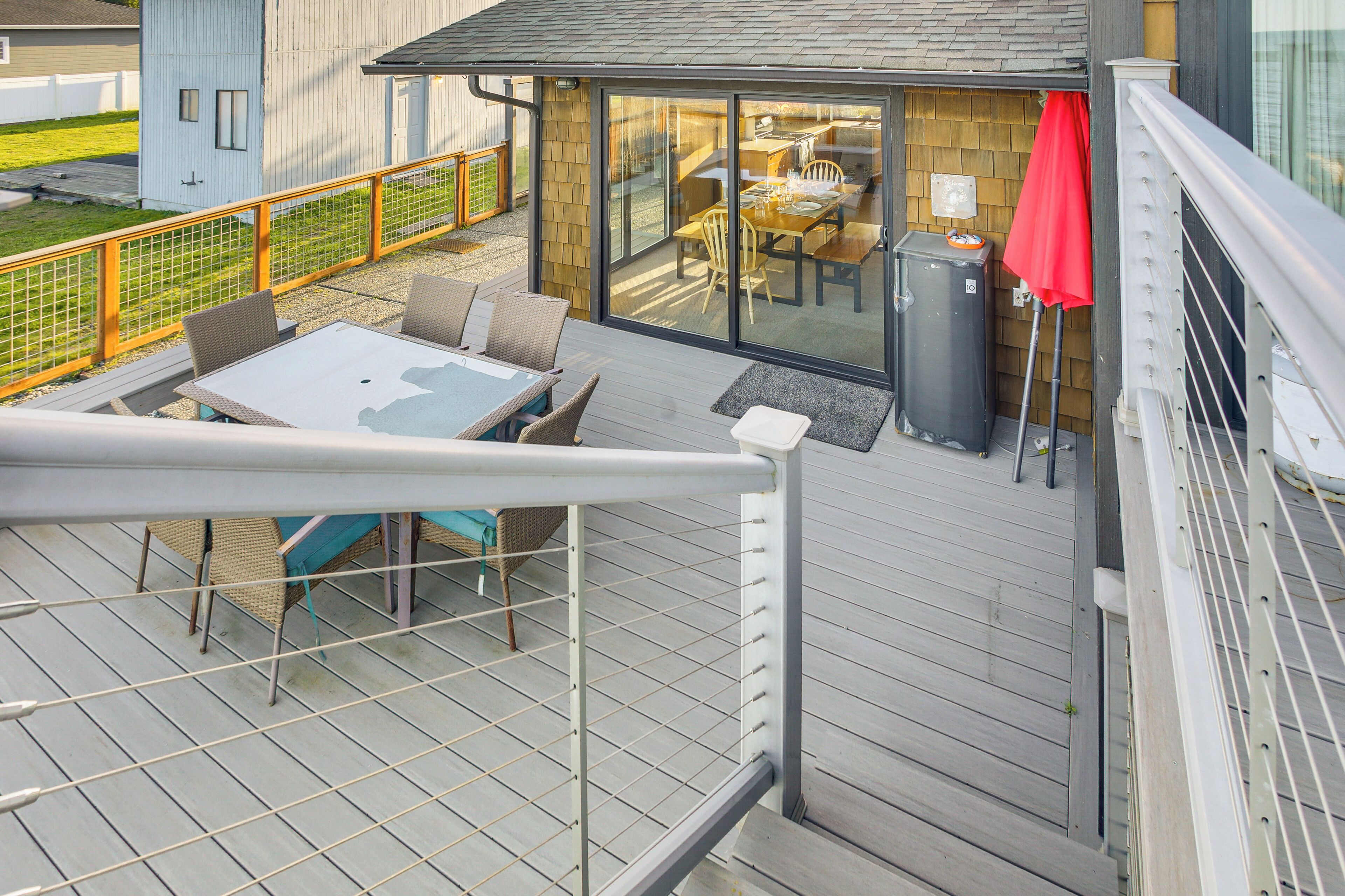 A deck with outdoor furniture, a sliding glass door leading to a dining area, and a trash can.