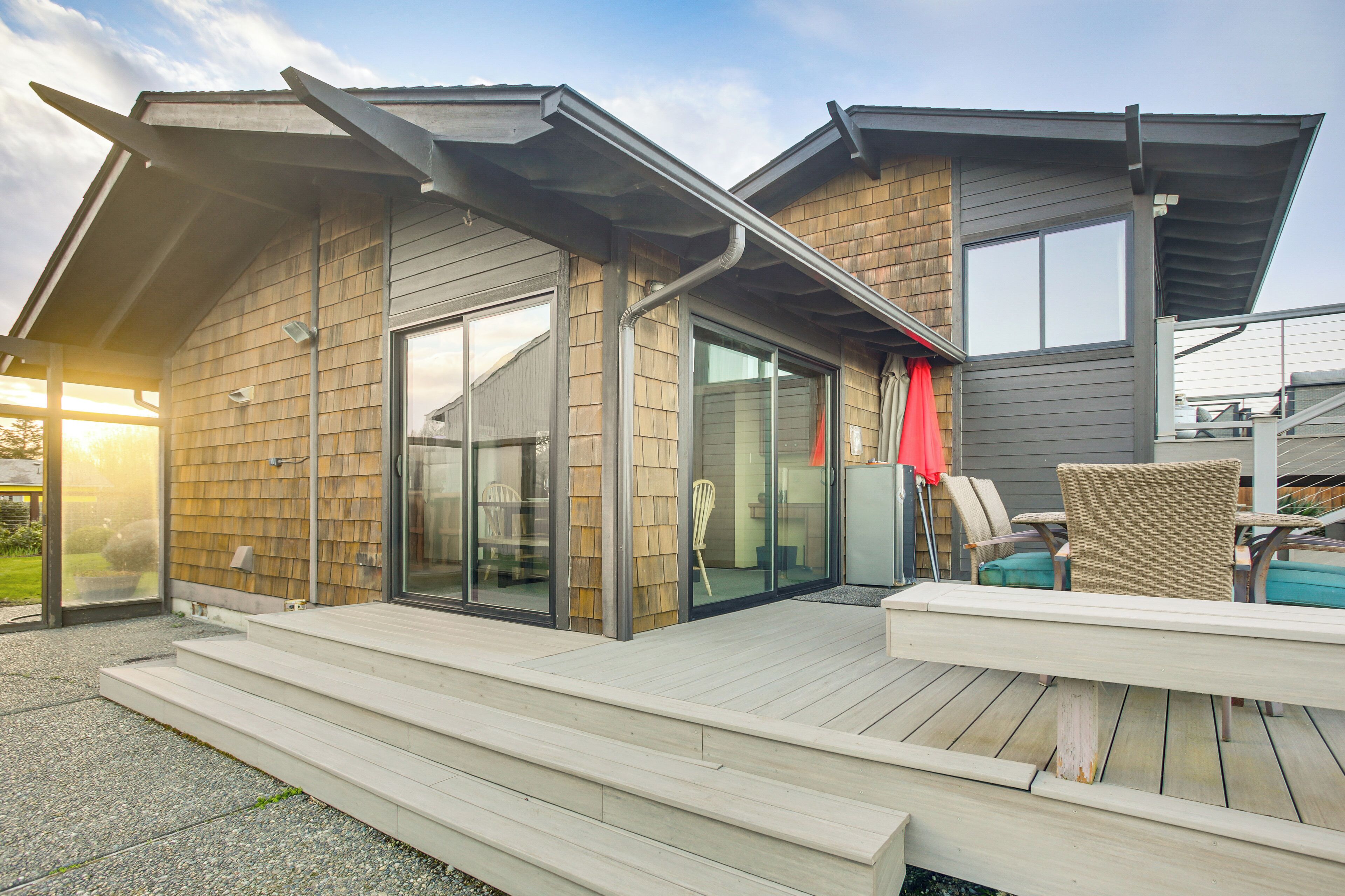 A modern house with a deck, large windows, and a covered outdoor seating area.