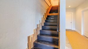 A staircase with wooden steps and a metal handrail, leading to a room with a white door.