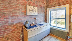 A kitchen with a brick wall, a window, and a sink.