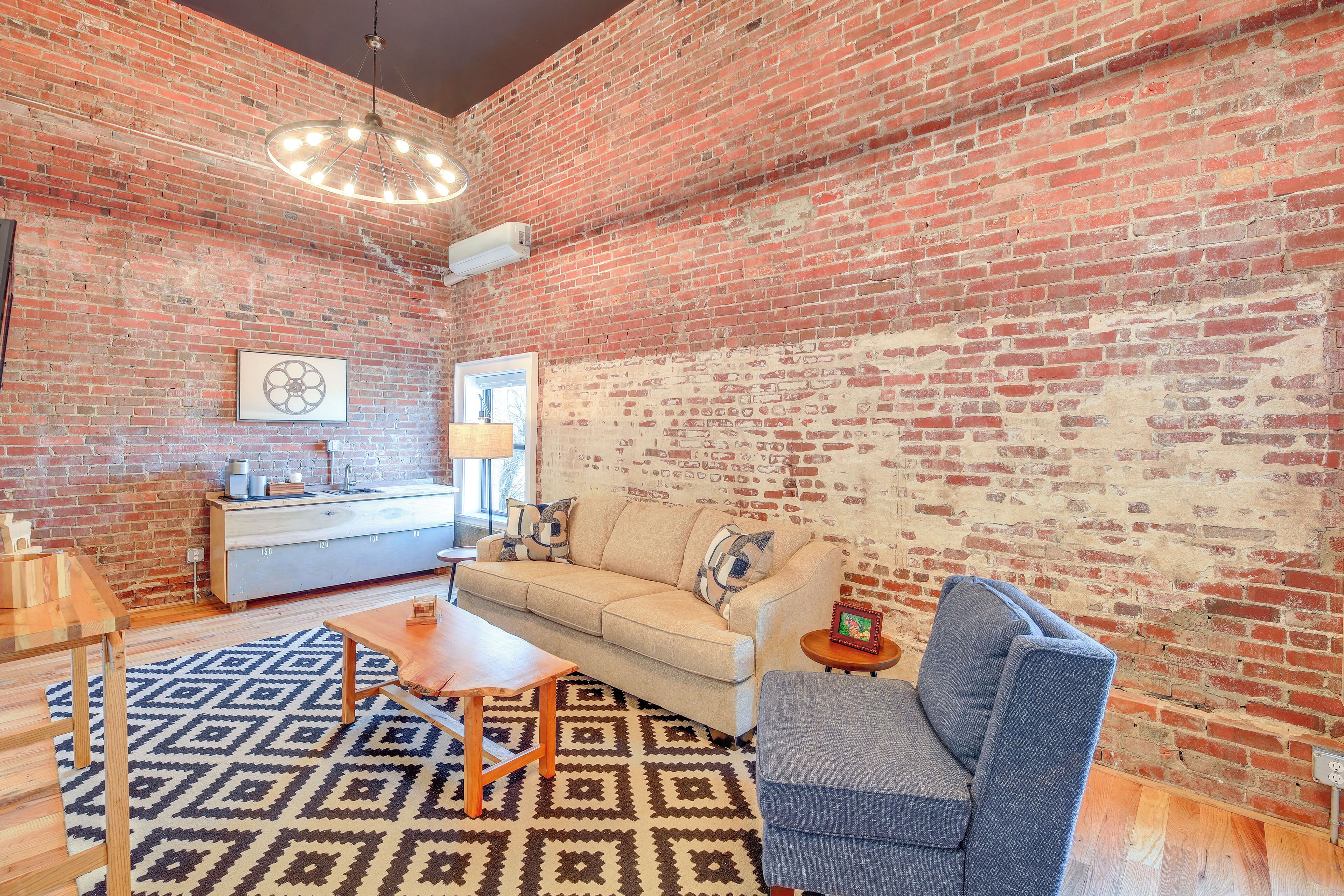 A living room with a brick wall, a sofa, a coffee table, and a patterned rug.