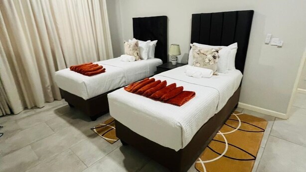 Ein Hotelzimmer mit zwei Betten, einem Schreibtisch, einer Lampe und einer Badezimmertür.