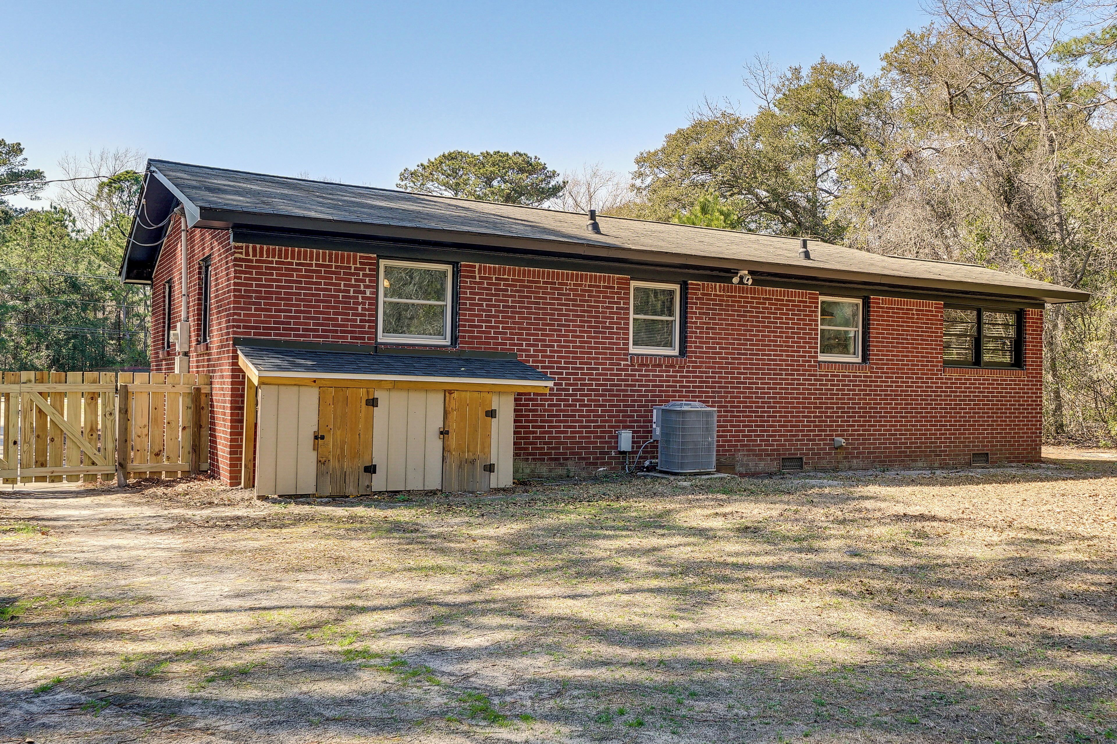 A single-story brick house with a garage, a fenced yard, and a clear sky.