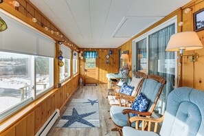 A wooden interior with a view of the outdoors, a star-patterned rug, and a seating area with chairs and a table. - Walk to Pigeon Hill Bay: Coastal Maine Cottage (Steuben)