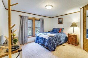 A bedroom with a bed, a nightstand, a lamp, a window with curtains, and a small plant. - Quiet Wooded Escape! Metro Detroit Basecamp (Romulus)