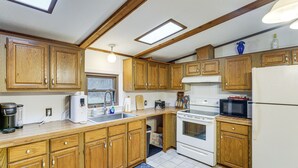 A kitchen with wooden cabinets, a white refrigerator, a stove, and a microwave. - Quiet Wooded Escape! Metro Detroit Basecamp (Romulus)