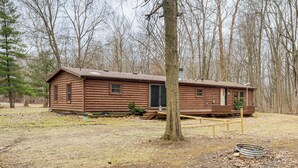 A log cabin with a front porch, a chimney, and a small deck. - Quiet Wooded Escape! Metro Detroit Basecamp (Romulus)